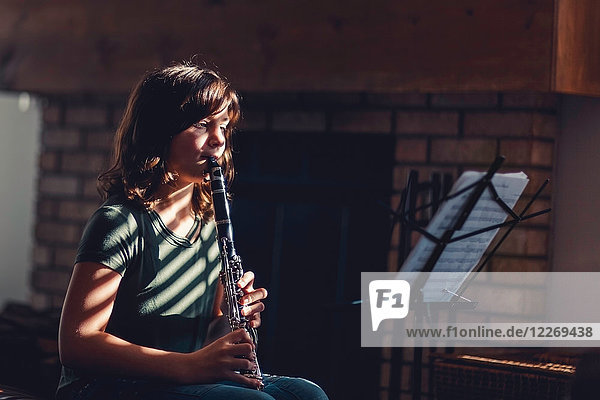 Girl at clarinet practice by fireplace