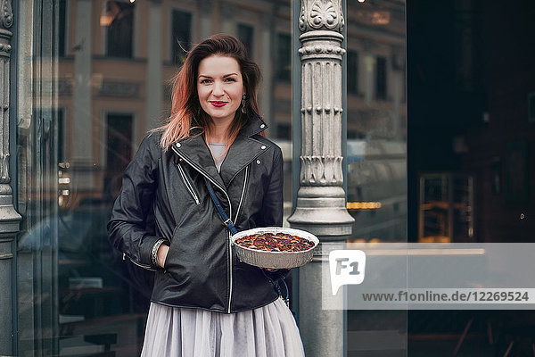 Porträt einer Frau auf der Strasse  die einen Teller mit Essen in der Hand hält