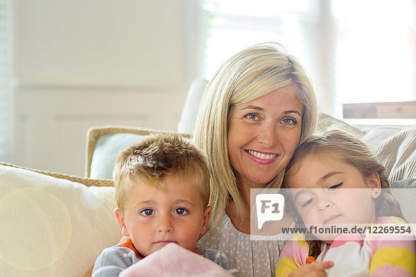 Mid adult woman with daughter and toddler son on sofa  portrait