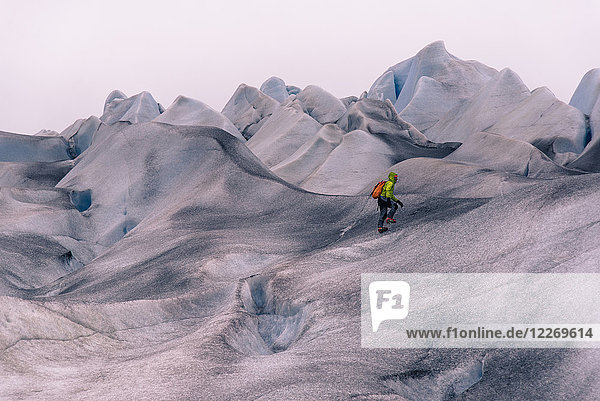 Männlicher Wanderer wandert über graue  schneebedeckte Landschaft  Narsaq  Vestgronland  Südgrönland
