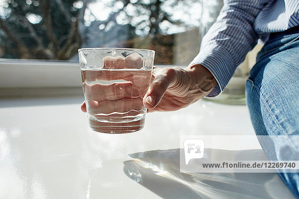 Ältere Frau hält ein Glas Wasser  Nahaufnahme