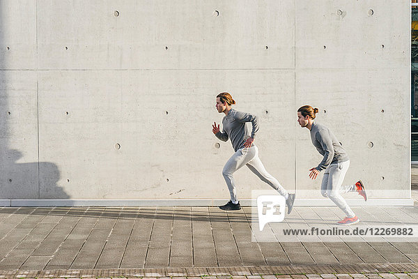 Young adult male twins running together  running up sidewalk