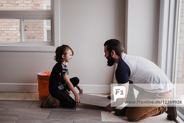 Girl helping father install floor tiles