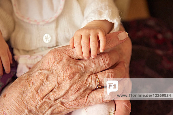 Ältere Frau hält Urenkelin mit Baby  Nahaufnahme der Hände