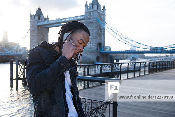 Junger Mann im Freien  benutzt ein Smartphone  Tower Bridge im Hintergrund  London  England  UK