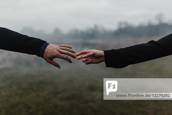 Schrägansicht eines jungen Paares  das Hände hält und sich mit den Fingern berührt