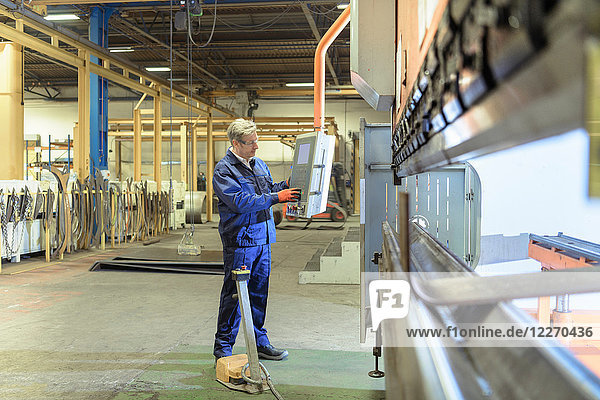 Engineer operating steel bending machine in engineering factory