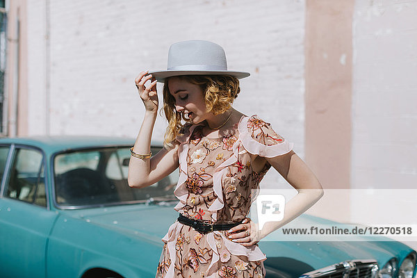 Frau mit Hut bei einem Oldtimer