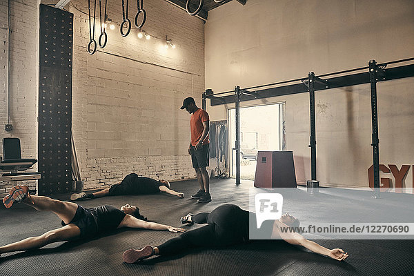 Gymnastiklehrer  der Personen beaufsichtigt  die im Fitnessstudio Bodenübungen machen
