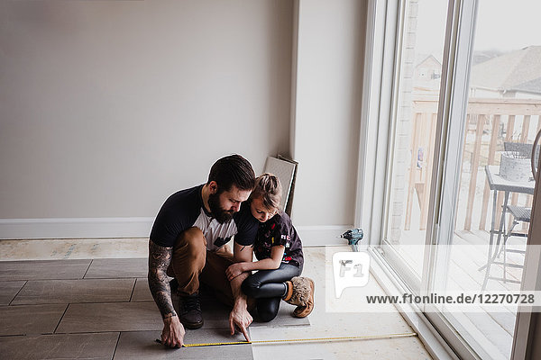 Mädchen hilft Vater beim Verlegen von Bodenfliesen