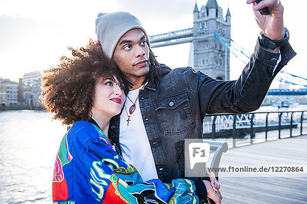 Junges Paar im Freien  Selbsthilfe mit Smartphone  Tower Bridge im Hintergrund  London  England  UK