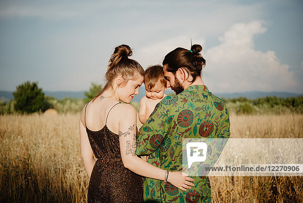 Couple with baby girl on golden grass field  Arezzo  Tuscany  Italy