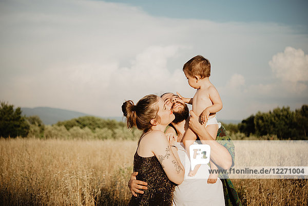 Couple with baby girl on golden grass field  Arezzo  Tuscany  Italy