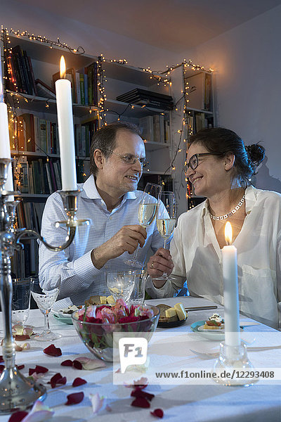 Paar stößt mit Champagnergläsern beim Candlelight-Dinner an