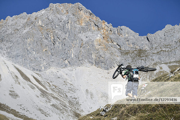 Mountain biker carrying bicycle on his shoulders