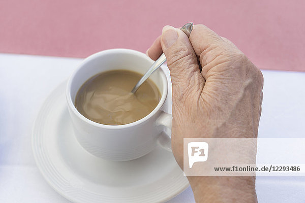 Nahaufnahme einer älteren Frau  die Kaffee umrührt