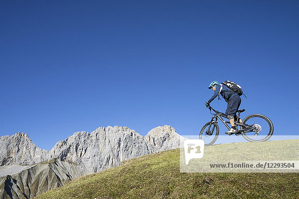 Mountain biker riding on uphill in alpine landscape