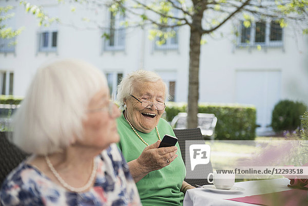 Senior woman laughing and using smartphone
