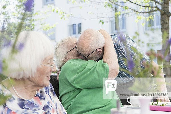 Ältere Menschen umarmen sich am Frühstückstisch