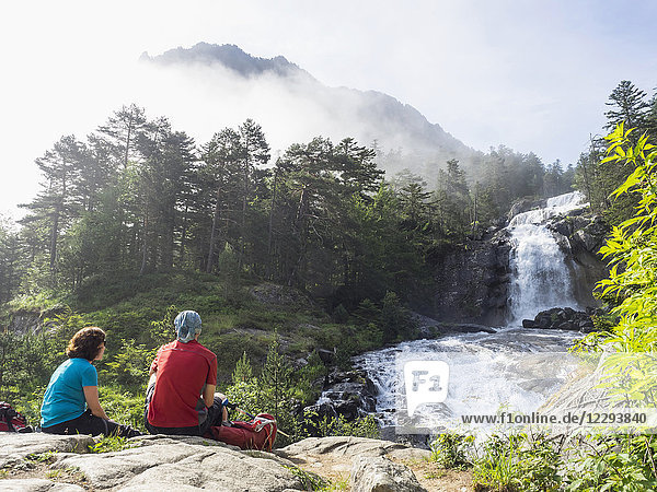 Hikers admiring scenic view of waterfall in Gave De Gaube river  France