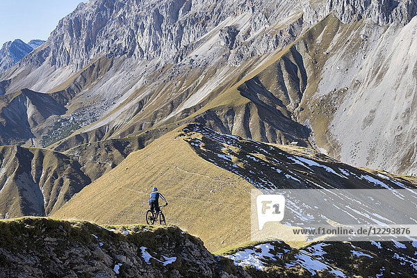 Mountain biker riding on uphill in alpine landscape