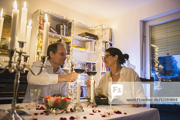 Ehepaar stößt mit Weingläsern bei einem Candlelight-Dinner an