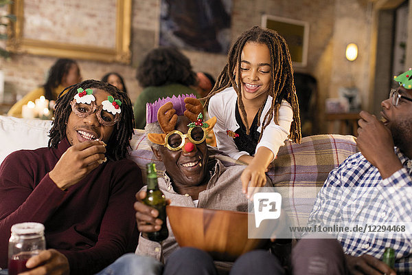 Verspielte Mehrgenerationen-Familie mit Weihnachtsbrille  die Popcorn genießt