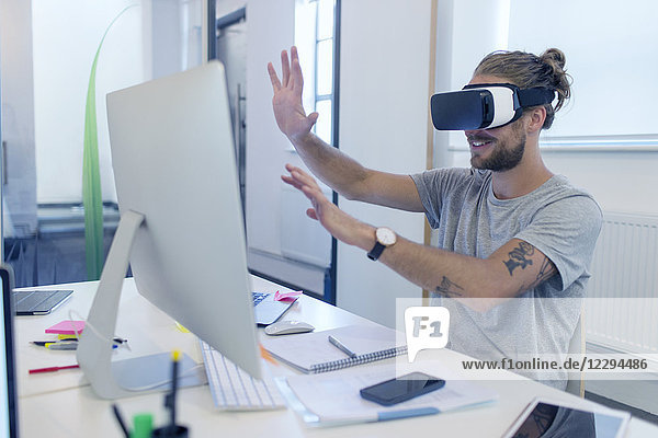 Männlicher Programmierer programmiert Virtual-Reality-Simulator Brille am Computer im Büro