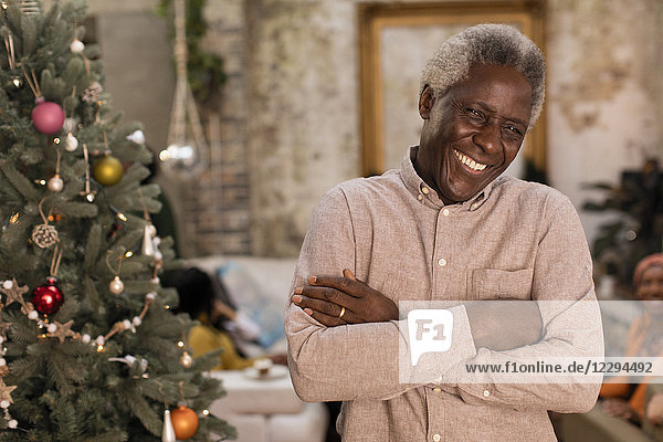 Portrait lächelnder  selbstbewusster Senior neben dem Weihnachtsbaum