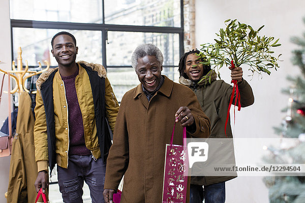 Happy grandfather and grandsons arriving with Christmas gift and mistletoe