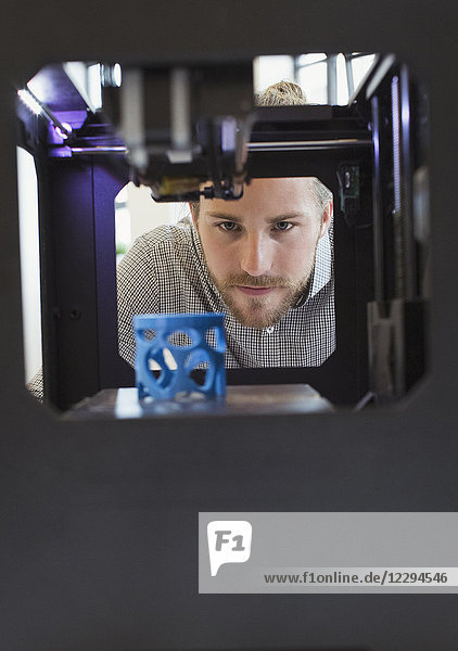 Fokussierter männlicher Designer beobachtet 3D-Drucker