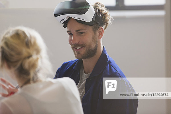 Smiling computer programmer wearing virtual reality simulator glasses