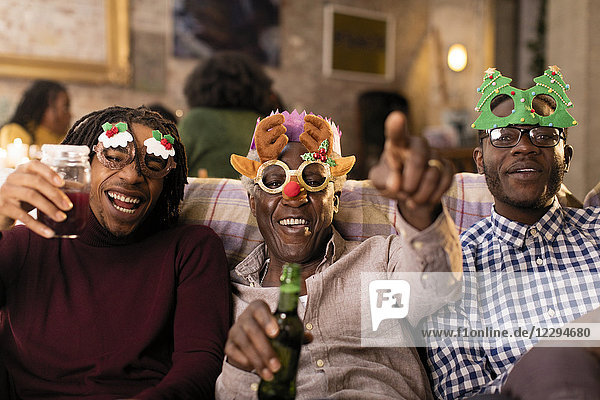 Portrait playful grandfather and grandsons wearing Christmas costume goggles