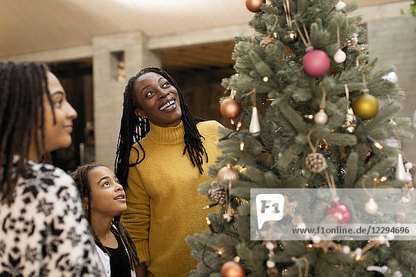 Mother and daughters looking up at Christmas tree