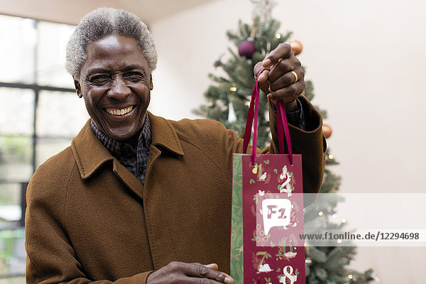 Portrait lächelnder älterer Mann mit Weihnachtsgeschenk