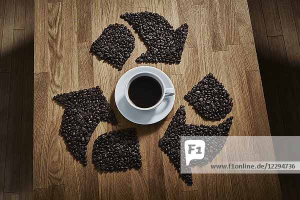 Kaffeebohnen als Recycling-Symbol um die Kaffeetasse herum