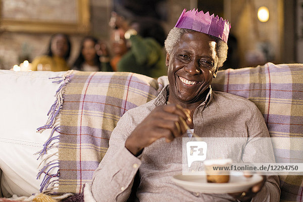 Portrait lächelnd  fröhlicher Senior mit Weihnachtspapierkrone  Dessert genießend