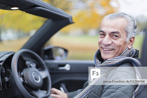 Porträt lächelnder  selbstbewusster Senior im Cabriolet