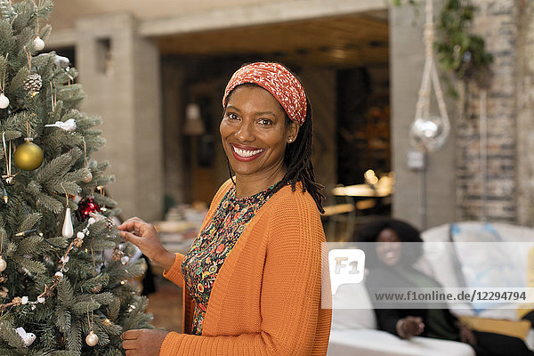 Portrait lächelnde  selbstbewusste Frau schmückt Weihnachtsbaum