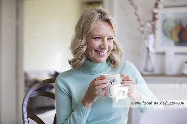 Lächelnde reife Frau trinkt Kaffee