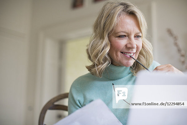 Smiling mature female freelancer working at laptop at home
