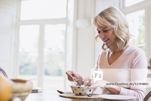 Smiling mature woman eating breakfast
