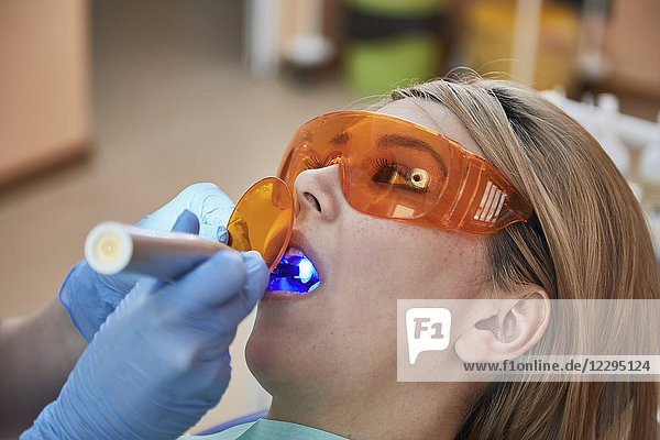 Abgeschnittenes Bild des Zahnarztes  der der Patientin eine Füllung gibt.