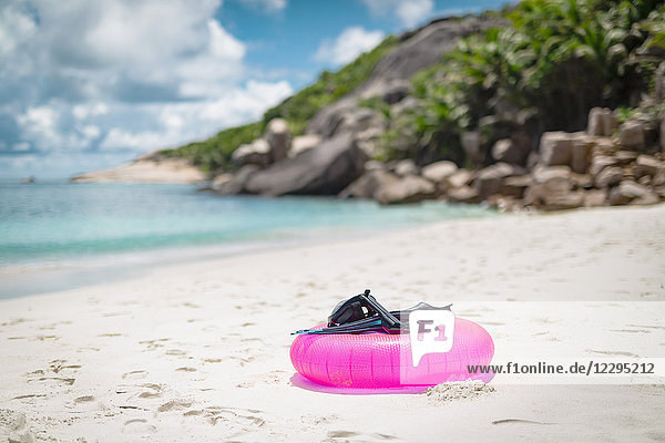Tauchflossen mit Tauchermaske und aufblasbarem Ring am Strand gegen bewölkten Himmel  Seychellen