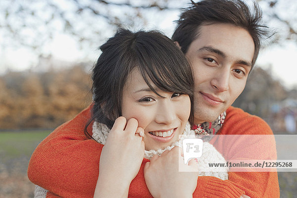 Smiling young couple embracing in park during winter