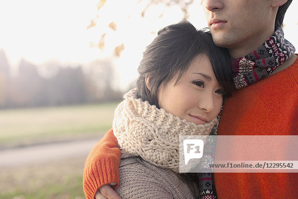 Smiling woman with embracing loving boyfriend in park during winter