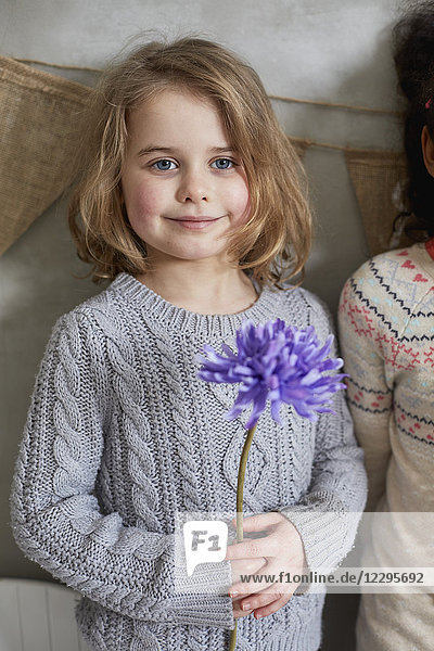 Porträt eines Mädchens mit violetter Blume  das mit einem Freund an der Wand steht.