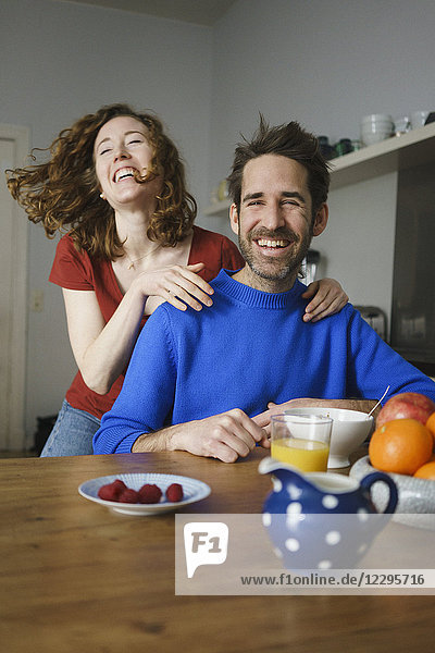 Porträt eines Mannes mit fröhlicher Frau am Tisch mit Frühstück im Zimmer