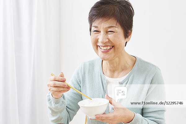 Japanische Seniorin isst Reis