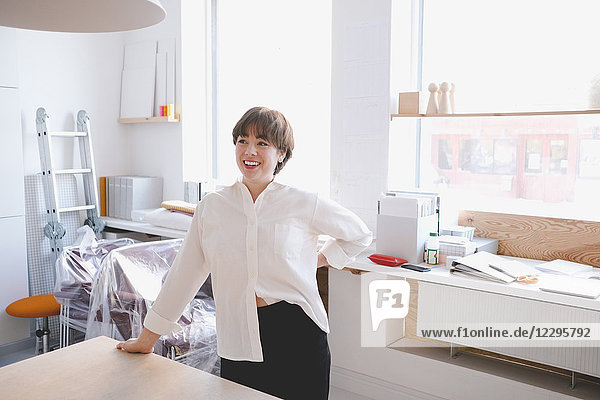 Smiling female design professional standing at desk in workshop